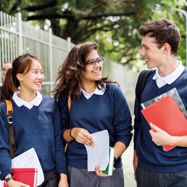 Tres adolescentes con uniforme de colegio caminando y conversando